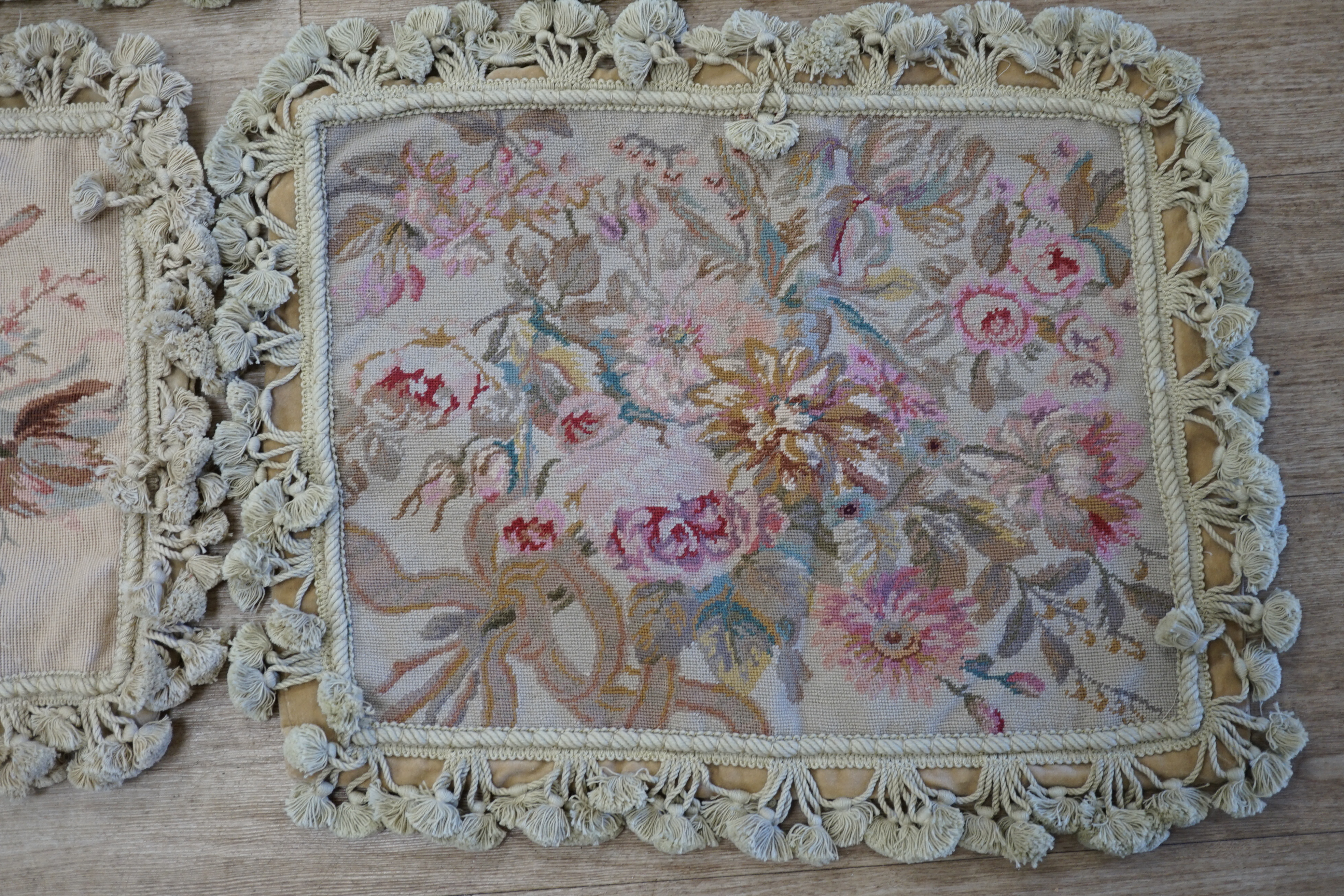 Three small square rose designed wool worked cushion covers and one similar larger cushion cover all with cotton tasselled edging, smaller covers 38cm square, larger cover 38cm x 48cm. Condition - good